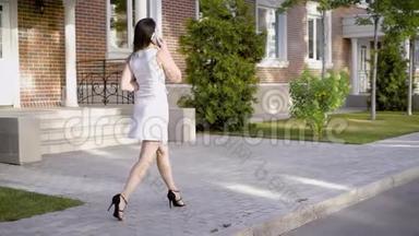 穿着漂亮<strong>白裙</strong>子的漂亮女人为了和她的朋友在电话里交谈而去散步